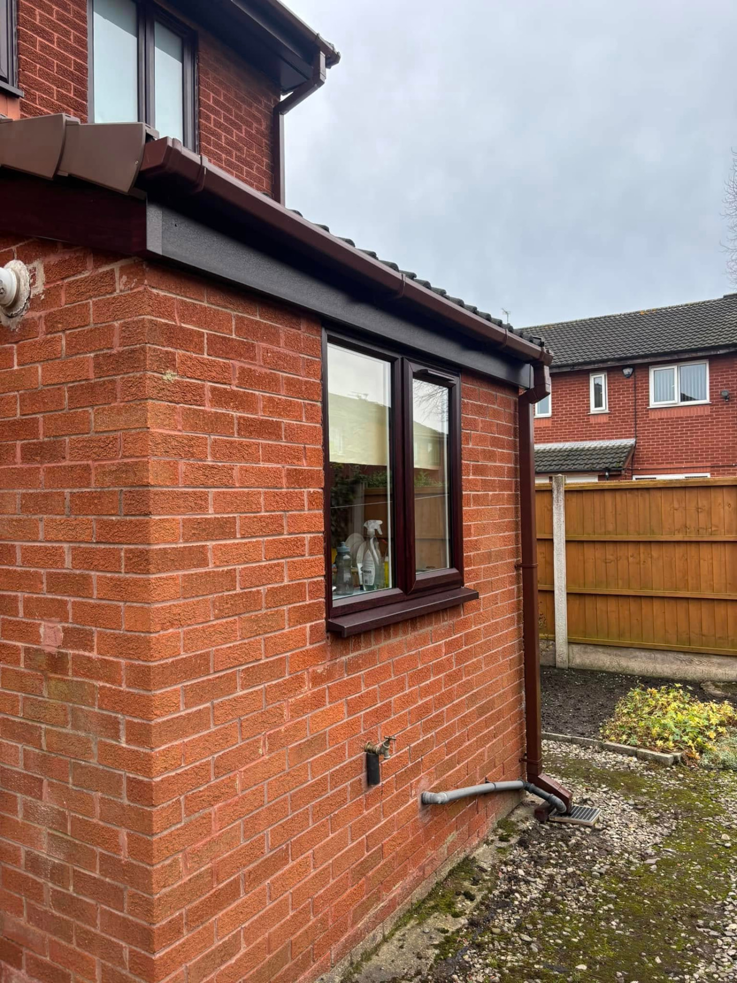 Brown fascias, soffits and downpipe on a brick house