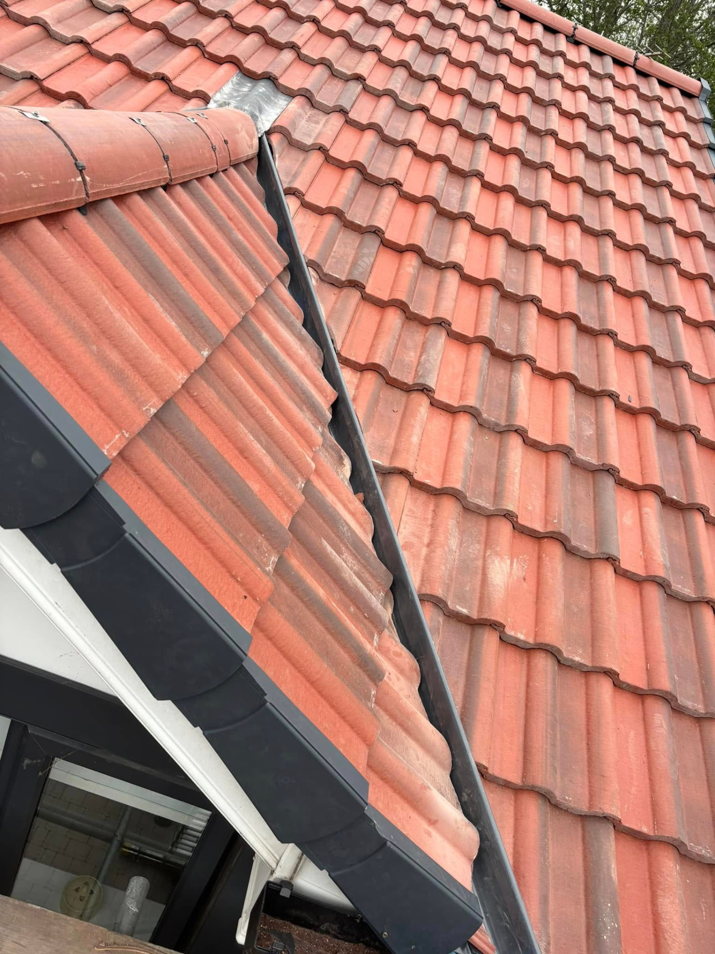 Close-up of a tiled roof with new dark grey fascias, soffits and guttering